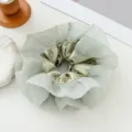 Gros plan d'élastique à cheveux en organza vert clair, détail de texture satinée élégante. - Chouchou Double Couche