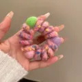 Close-up detail of colorful woolen yarn wrapped telephone wire hair scrunchie with cute balls. - Pink
