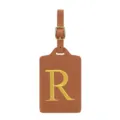 Vue détaillée de l'étiquette de bagage en cuir PU marron avec lettre R brodée dorée et une boucle. - Lettre R