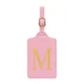 Dettaglio dell'etichetta bagaglio in ecopelle rosa con lettera M ricamata in oro e fibbia. - Rosa M