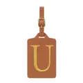 Détail d'étiquette de bagage en cuir PU marron, boucle dorée et lettre U brodée. - Lettre U