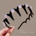 Close-up detail of a stylish black wavy hair hoop with iridescent pearl beads for women. - Purple