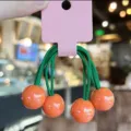 Cute candy-colored spherical hair ties detail view, green elastic bands with orange beads. - Orange