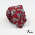 Close-up detail of a red men's necktie featuring an elegant white floral jacquard pattern. - 011
