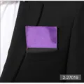 Detailed view of a purple pocket square neatly folded in a black suit breast pocket. - Purple