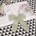 Close-up detail of a sage green fabric JK uniform bow tie with elastic strap, elegant style. - 015