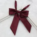 Detailed view of burgundy JK uniform bow tie, fine ribbed fabric with pointed long handle design. - 010-Wine Red