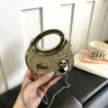 Detailansicht der goldenen glitzernden Acryl-Handtasche mit Metallring und Schulterkette. - Gold