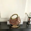 Detailaufnahme der goldenen Acryl Abendtasche mit roten Strasssteinen und Metallring. - Rot