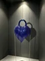 Vue détaillée d'un superbe sac de soirée cœur en strass bleu avec franges délicates. - A136 bleu