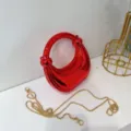 Glänzende rote metallische Kreis Mini Handtasche Detailaufnahme mit goldener Kette. - Rot