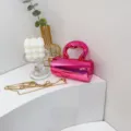 Glänzende rosa zylindrische Handtasche mit einzigartigem Griff und Goldkette, Detailansicht. - Rosa (C011)