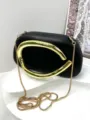 Squisito dettaglio della maniglia in metallo dorato su elegante borsa nera da sera. - Nero