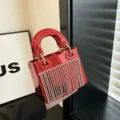 Dettaglio borsa da sera in acrilico rosso lucido con frange di strass e manici metallici. - C025 rosso