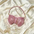 Close-up detail of a stunning pink rhinestone bow evening clutch bag with crystal handle. - Pink