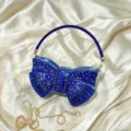 Detailed view of the blue acrylic crystal bow evening clutch with beaded handle and gold chain. - Blue