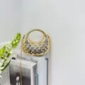 Close-up of the stylish metallic gold mini handbag with circular handle and chain strap. - Gold