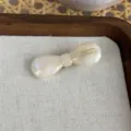 Nahaufnahme der cremefarbenen Acetat Schleifen-Haarspange mit feiner Textur und Aufdruck. - Weiß