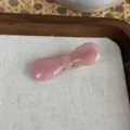 Nahaufnahme einer süßen rosa Acetat Schleifen Haarklammer auf Holztablett, elegant. - Hellrosa