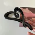 Primer plano detallado de una elegante pinza para el cabello en forma de corazón negro. - Negro Brillante