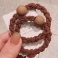 Detailed close-up of brown braided hair tie with matte bead, stylish ponytail holder. - Light Coffee