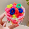 Primo piano di mini elastici in spugna colorati in vaso trasparente, morbidi ed elastici. - Stile Misto 1