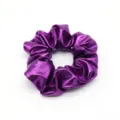 Detailed close-up of a shiny purple metallic hair scrunchie showing fabric texture and elastic design. - Purple