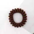 Brown telephone cord hair tie close-up, fabric wrapped elastic spiral hair band detail shot. - Coffee