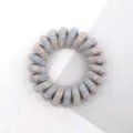 Detailed close-up of a multi-color woven spiral telephone wire hair tie with pastel texture. - Multicolor Light Cool Tone