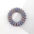 Detailed close-up of a colorful retro woven telephone wire hair tie elastic band. - Multicolor Blue Purple