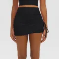 Close-up detail of black high-waist ruched yoga skort with side drawstring design. - S / Bottoms / Premium Black