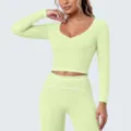 Detail van lichtgroene sport-croptop met lange mouwen en contrasterende witte bies. - S / Tops / Citroengroen