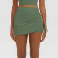 Green athletic yoga skirt detail view featuring high waist, side ruching, and built-in shorts. - S / Bottoms / Green