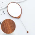Tragbarer ovaler Hand-Schminkspiegel mit Holzmaserung, Metallstange und dekorativem Perlenstift. - Holzmaserungsfarbe Nr. 2