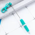 Portable mini ballpoint pen with keychain clip, turquoise and silver design for gift. - Teal