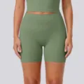 Close-up detail of high-waisted green yoga shorts and matching activewear top, breathable. - S / Cedar Green