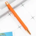Stylo à bille rétractable élégant avec corps orange caoutchouté et détails or rose. - Orange