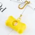Yellow bone-shaped dog waste bag dispenser with metal carabiner for outdoor walking. - Yellow