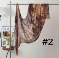 Detail view of a brown tie-dye pleated scarf hanging on a rack with a stylish background. - Pattern #2