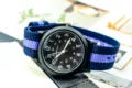 Detailed close-up shot of quartz military watch with blue nylon strap and black dial. - Blue, Purple & Blue