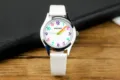 Nahaufnahme der Kinderuhr mit weißem Zifferblatt, bunten Ziffern und weißem Armband. - Weiß