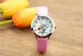 Vista detallada del reloj infantil con correa de cuero rosa y esfera de fantasma. - Rosa
