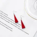 Close-up of red wooden triangle dangle earrings placed on white paper with text. - Solid Red Triangle Style (12)