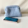 Handcrafted blue crochet clutch bag with metal frame closure, stylish fabric texture detail. - Blue