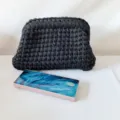 Handmade crochet clutch bag detail, dark grey fabric texture, minimalist daily fashion accessory. - Black