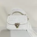 Handmade white crochet bag detail showcasing the woven texture, gold lock, and stylish tassel. - White