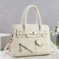 Détail élégant de sac à main beige pour femme avec design structuré, fermoir en métal et fermeture. - Blanc Cassé
