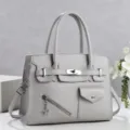 Détail de sac à main gris avec serrure métallique, poignées robustes et poche avant. - Gris