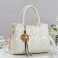 Nahaufnahme der eleganten, beige Henkeltasche mit schickem Muster und feinen Metalldetails. - Gebrochenes Weiß