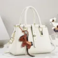 Detailansicht der weißen Vintage Handtasche mit goldener Hardware und braunem Pferdeanhänger. - 28/14/20 / Weiß